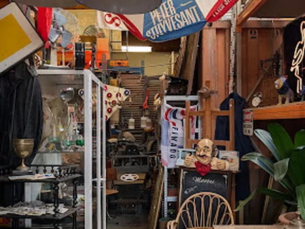 Binnenaanzicht van kringloopwinkel met diverse tweedehands spullen, stellingen, kleding, meubels en decoratieve items