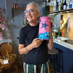 Vrouw toont roze decoratief blikje met ster- en oogmotief