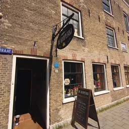 Bakstenen gevel van vintage winkel aan Ankerstraat met zwarte deur, ramen en uithangbord
