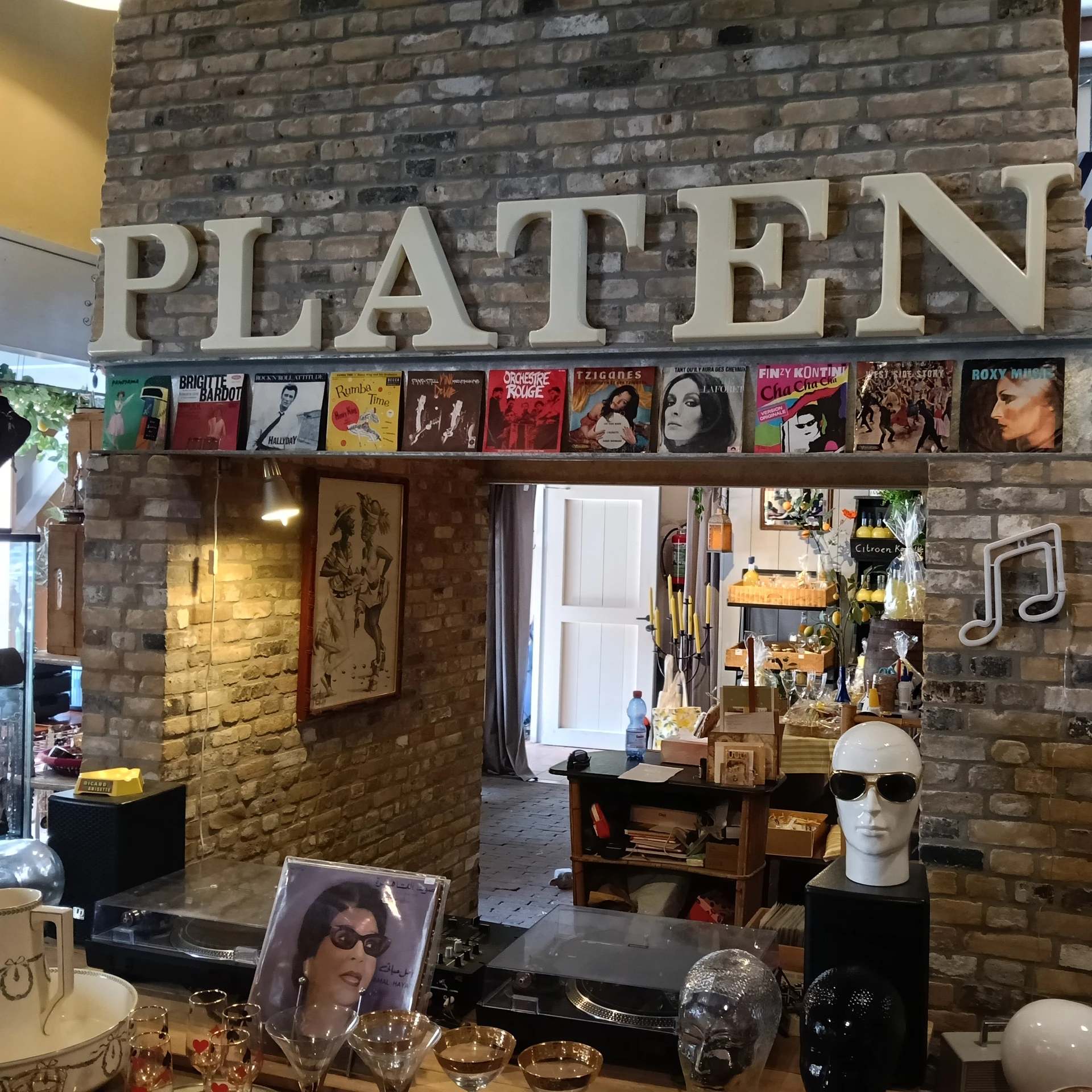 Winkelinterieur met bakstenen muur, vintage platen aan de muur, stellingen met merchandise en decoratieve items