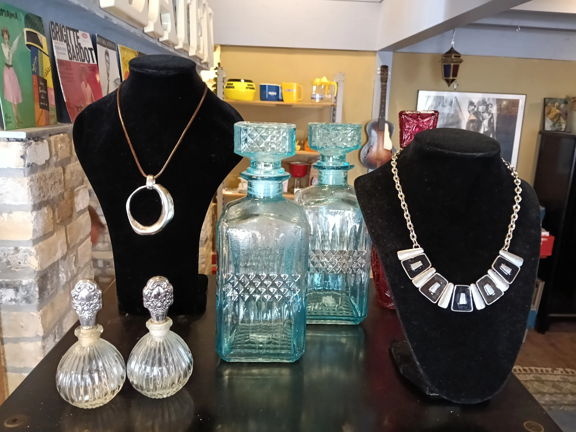 Vitrinedisplay met sieraden, kristallen flessen en accessoires op etalagepoppen
