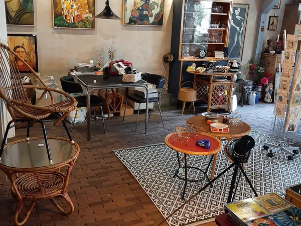 Vintage winkelinterieur met retro meubels, tafels, stoelen en decoratieve objecten onder kunstwerk aan de wand