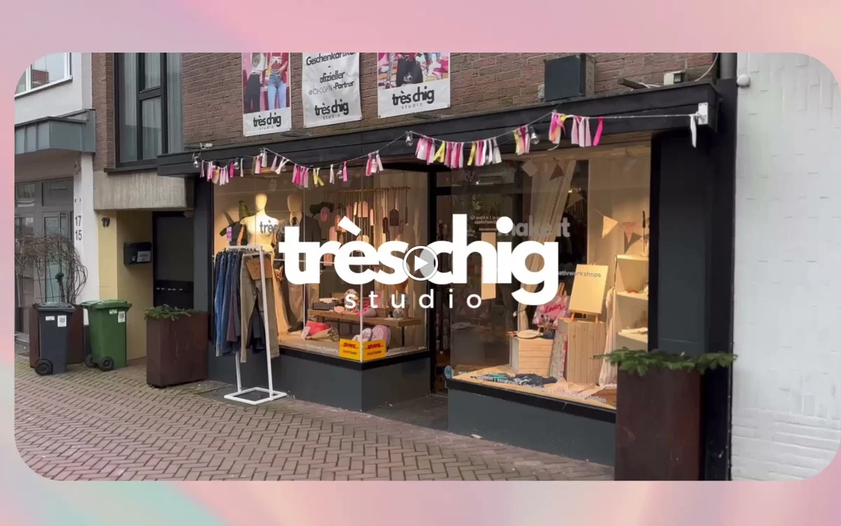 Winkelfront met glazen pui, winkelnaam 'treschhig studio' in witte letters, decoratieve slingers en uitgestalde kleding in et