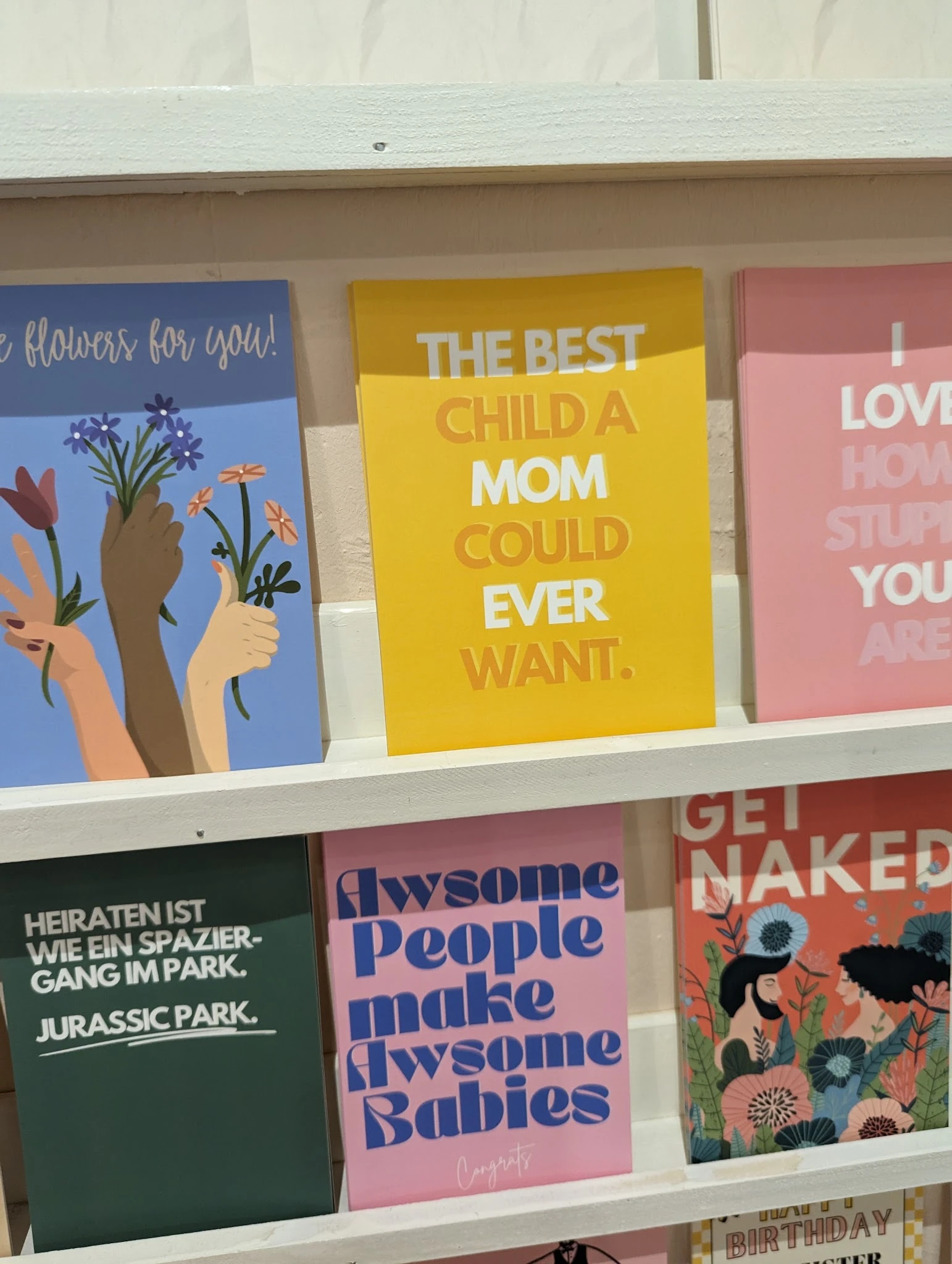 Greetingcards en posters met kleurrijke afbeeldingen en motiverende teksten op een winkelplank
