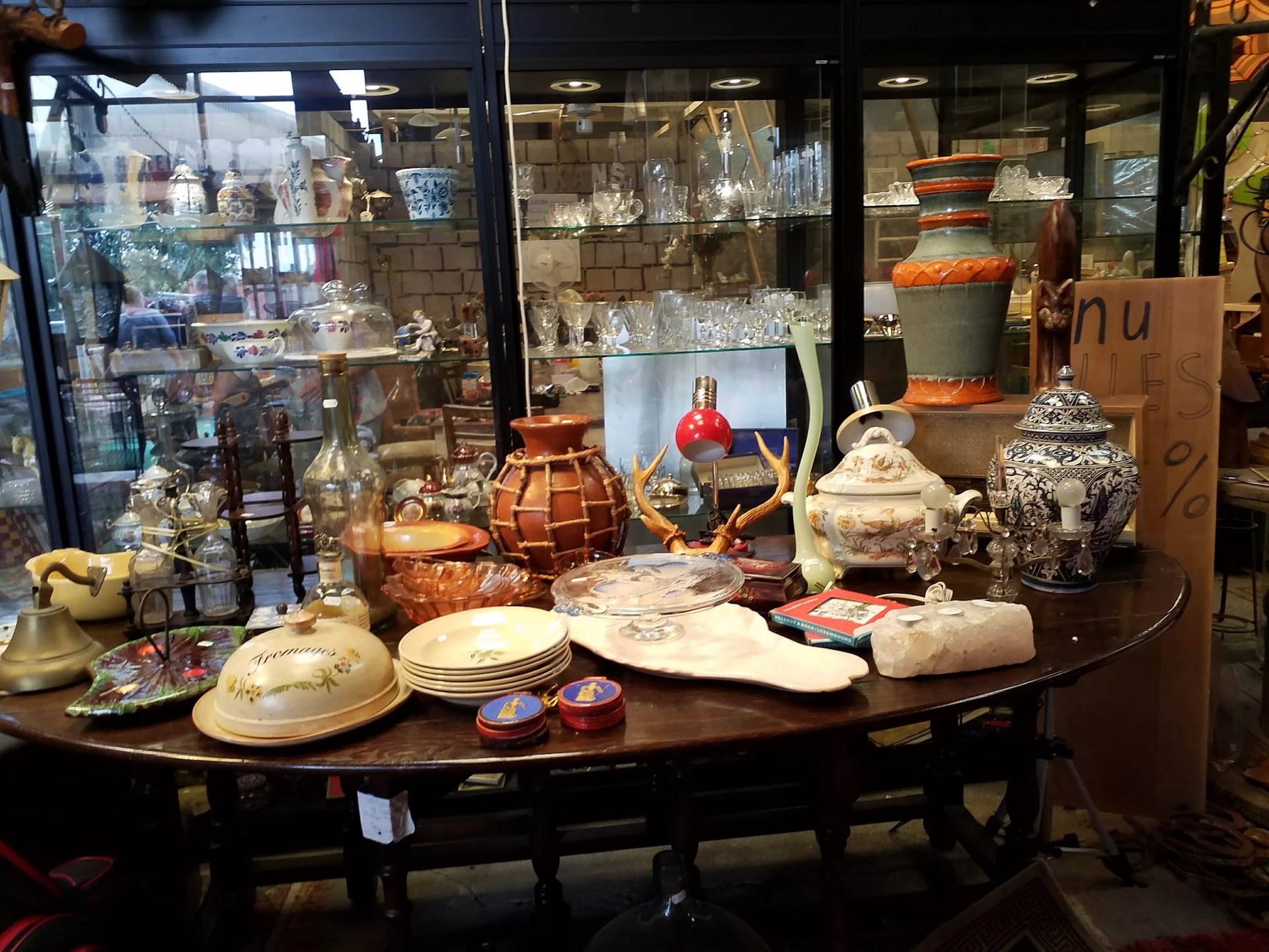 Uitgestalde serviesgoed, decoratieve items en antieke voorwerpen op tafel in de kringloopwinkel