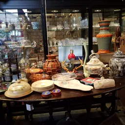 Uitgestalde serviesgoed, decoratieve items en antieke voorwerpen op tafel in de kringloopwinkel