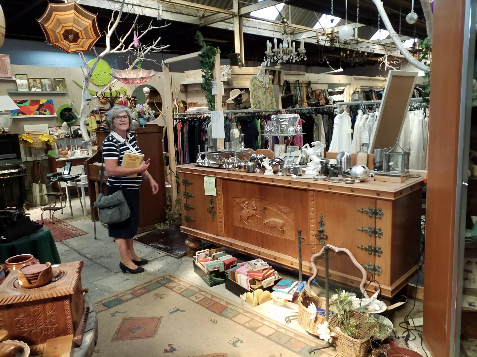 Winkelbinnenruimte met houten toonbank, vitrine, rekken met kleding en diverse vintage spullen