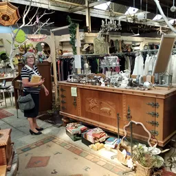 Winkelbinnenruimte met houten toonbank, vitrine, rekken met kleding en diverse vintage spullen