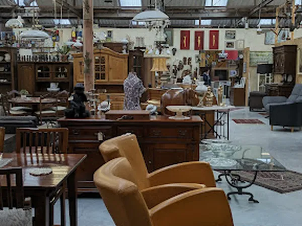 Winkelvloer van kringloopwinkel met meubels, kasten, stoelen en diverse spullen verspreid door de ruimte