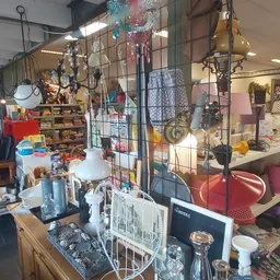 Binnenkant van kringloopwinkel met diverse spullen en meubels op stellingen en aan het plafond