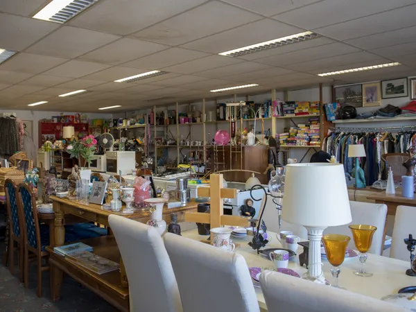 Winkelvloer van kringloopwinkel met tafels, stellingen, kleding en diverse tweedehands spullen