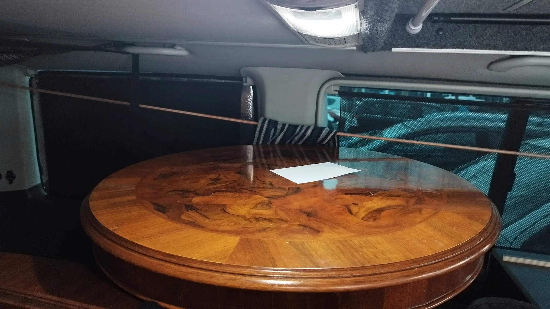 Ronde houten tafel met ingelegd patroon, opgesteld in een kringloopwinkel