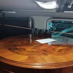 Ronde houten tafel met ingelegd patroon, opgesteld in een kringloopwinkel