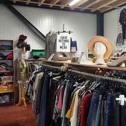 Winkelinterieur met kledingrekken, stellingen met tweedehands spullen en decoratieve items