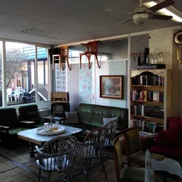 Woonkamer-achtige winkelruimte met zwarte zitmeubels, boekenrek, salontafel en grote ramen met daglicht