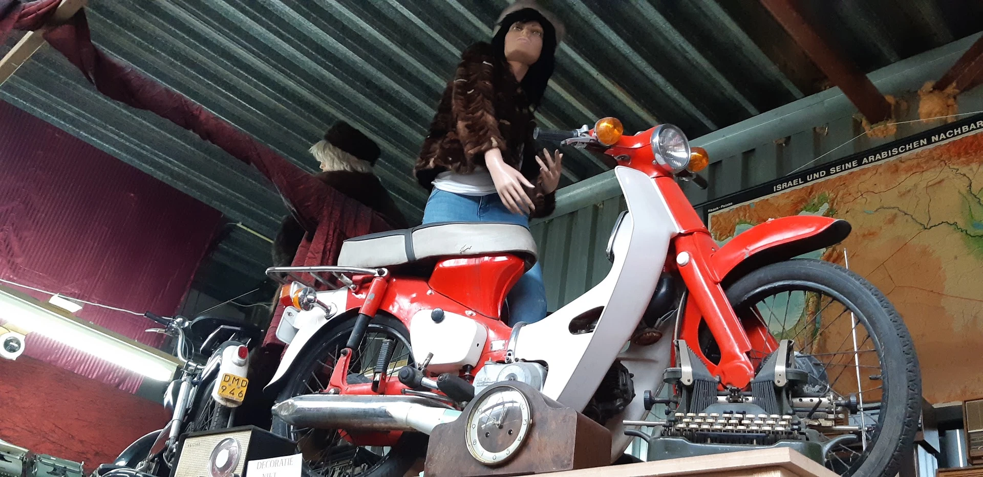 Rode en witte vintage scooter met een mannequin erop in de winkel