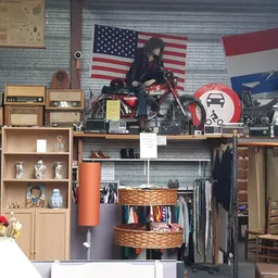 Winkelinterieur met stellingen, kleding op hangers, decoratie met Amerikaanse vlag en motorfiets op display