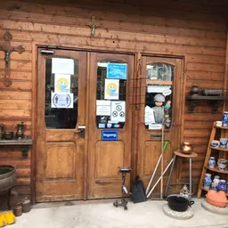 Houten winkelinterieur met ingangsdeuren, stellingen met diverse spullen, klok aan muur en winkelattributen