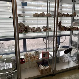 Glazen vitrinekast met aardewerk, beeldjes en decoratieve objecten uit de tweedehandswinkel