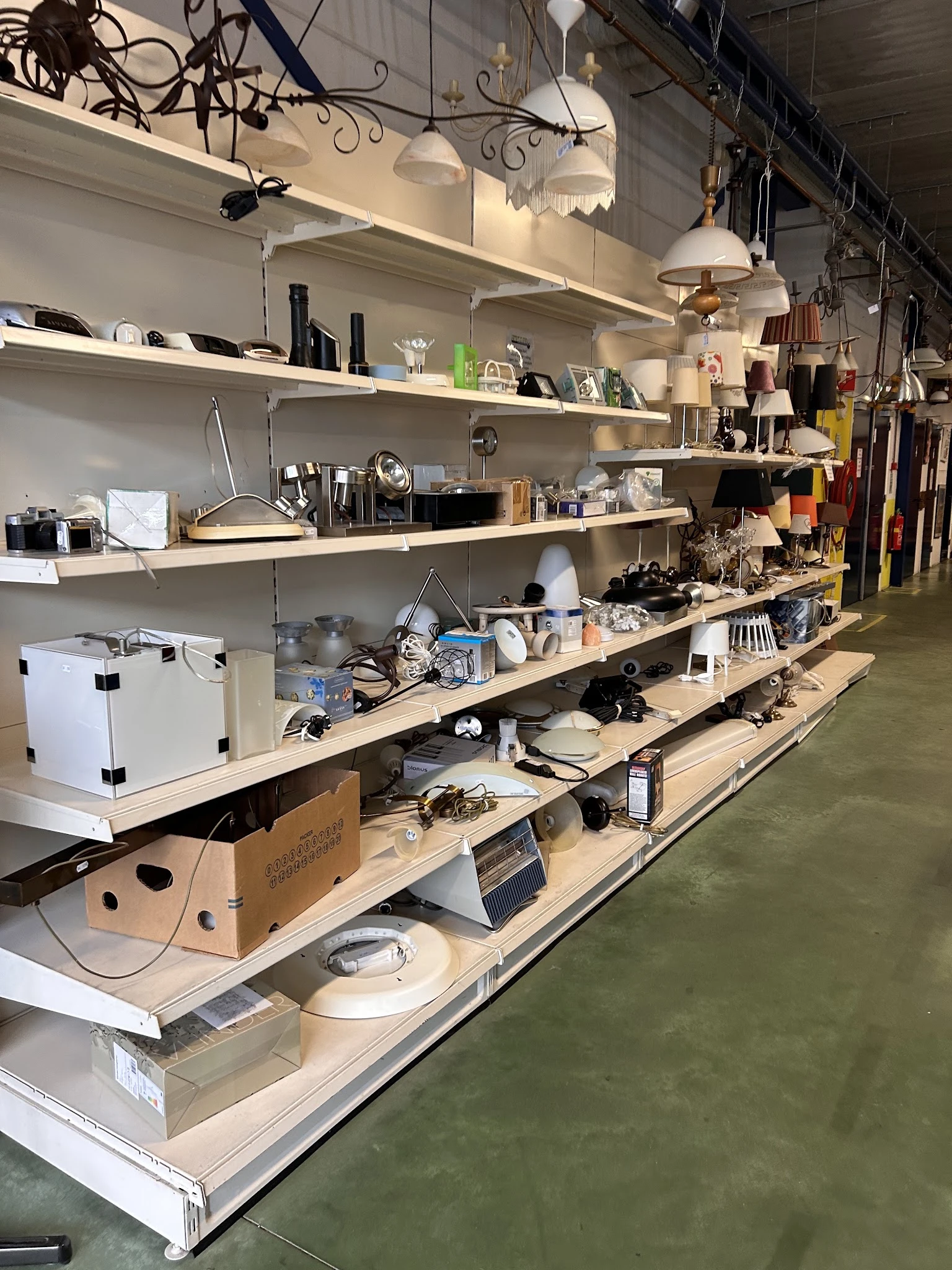 Houten stellingen met diverse huishoudelijke artikelen, keukengerei en elektronische spullen