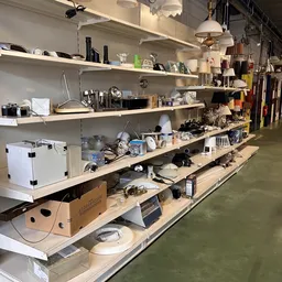 Houten stellingen met diverse huishoudelijke artikelen, keukengerei en elektronische spullen