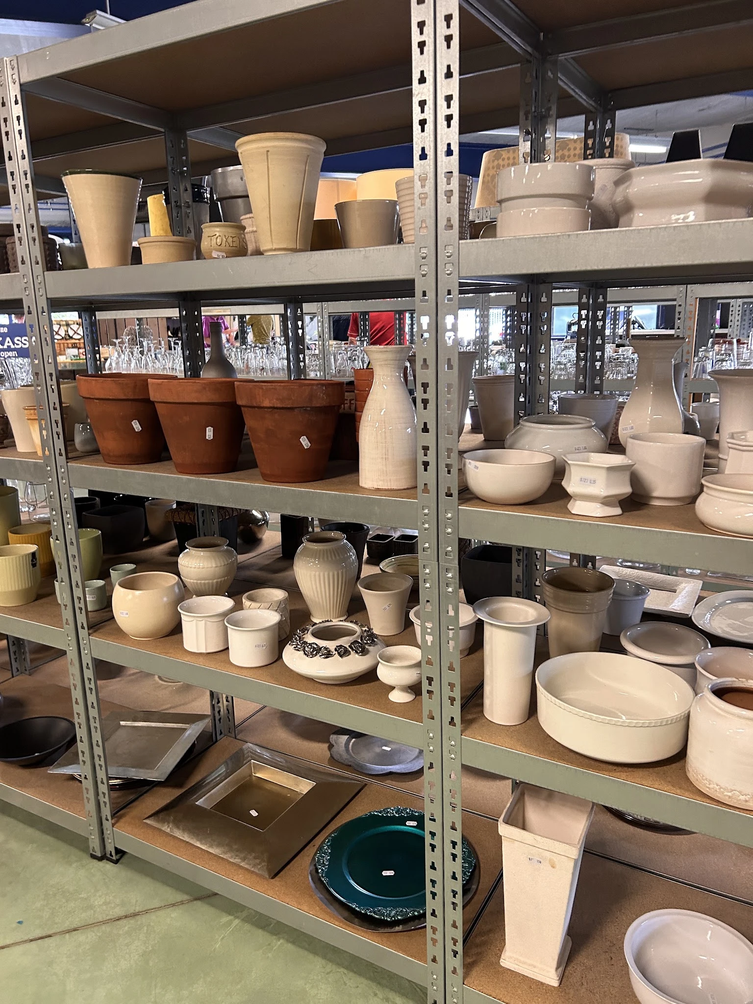 Stellingen met aardewerk, servies en keramische huishoudartikelen in verschillende maten en kleuren