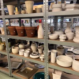 Stellingen met aardewerk, servies en keramische huishoudartikelen in verschillende maten en kleuren
