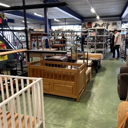 Winkelvloer met diverse meubels waaronder houten babyboxen, tafels en andere tweedehands spullen