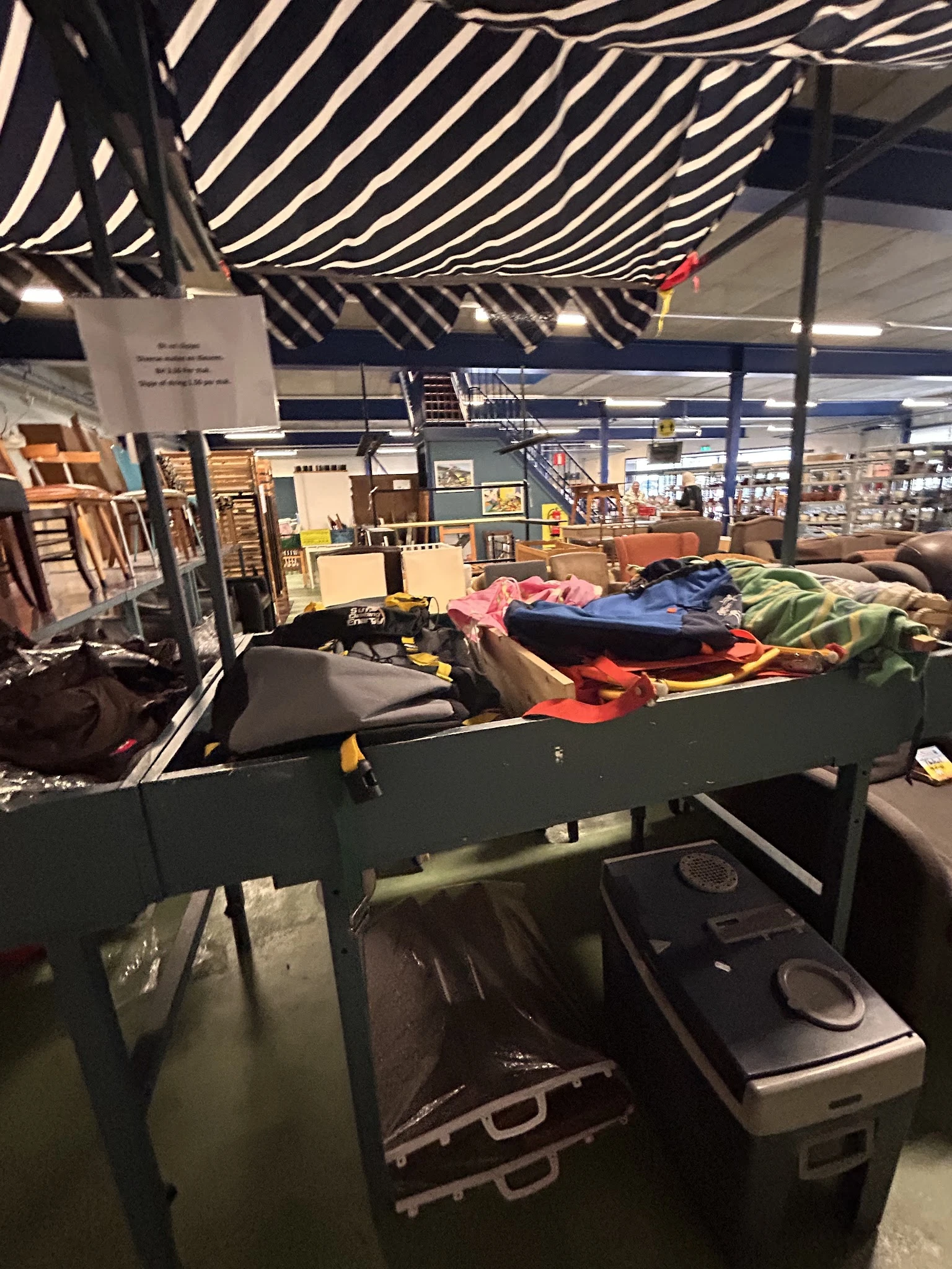 Tafel vol met kleding in verschillende kleuren in een kringloopwinkel