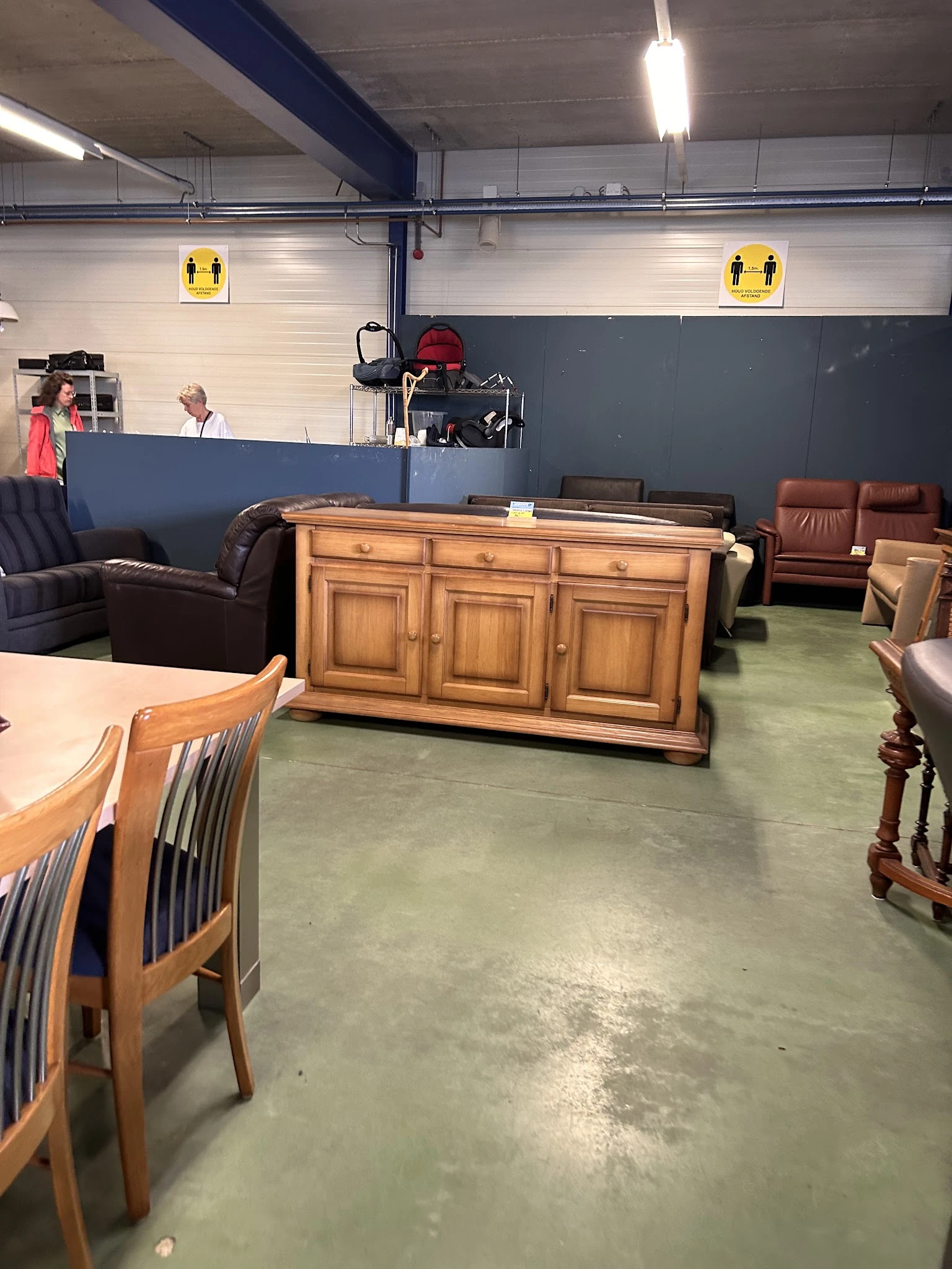 Winkelvloer met verschillende meubels: houten dressoir, bruine leren stoelen, houten stoelen en andere inboedelartikelen