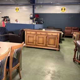 Winkelvloer met verschillende meubels: houten dressoir, bruine leren stoelen, houten stoelen en andere inboedelartikelen