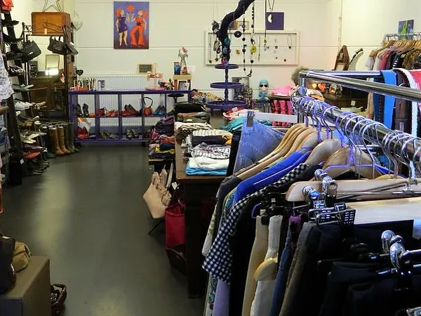 Interieur van kringloopwinkel met kledingrekken, speelgoed en diverse spullen