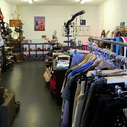 Interieur van kringloopwinkel met kledingrekken, speelgoed en diverse spullen