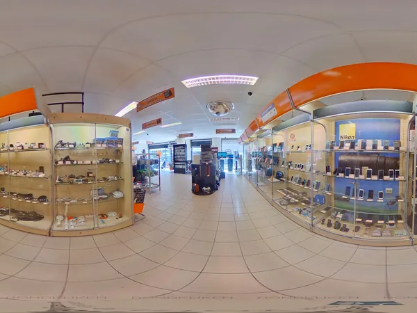 Panoramisch overzicht van een kringloopwinkel met vitrineksten en stellingen met producten langs de wanden