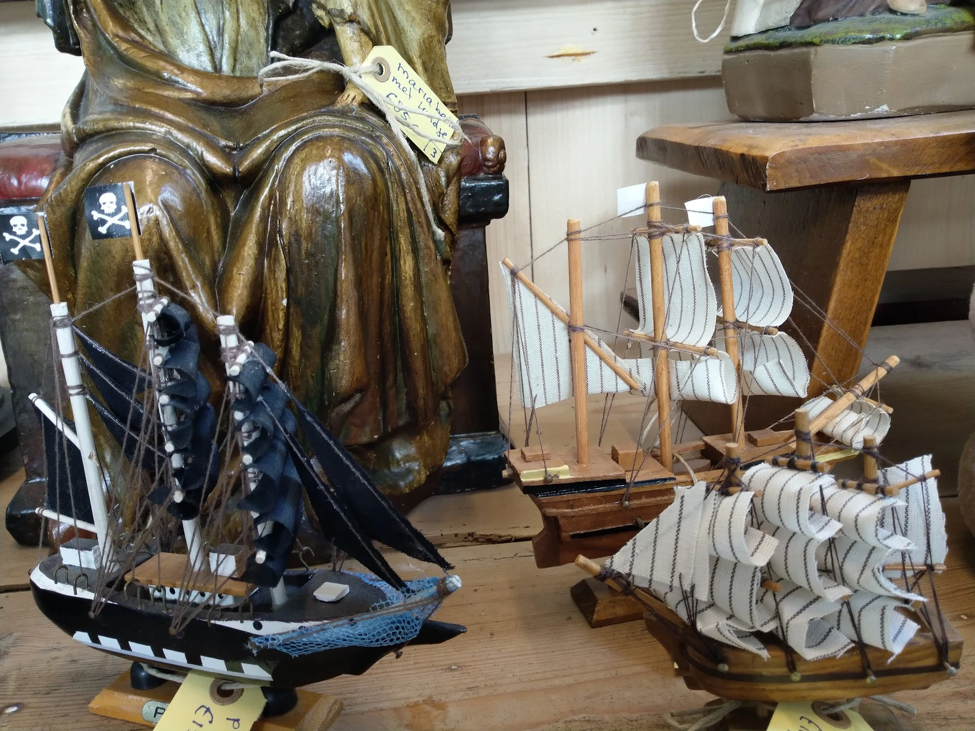 Tweedehands decoratieve items: houten scheepsmodellen en een bronzen beeld op houten voet