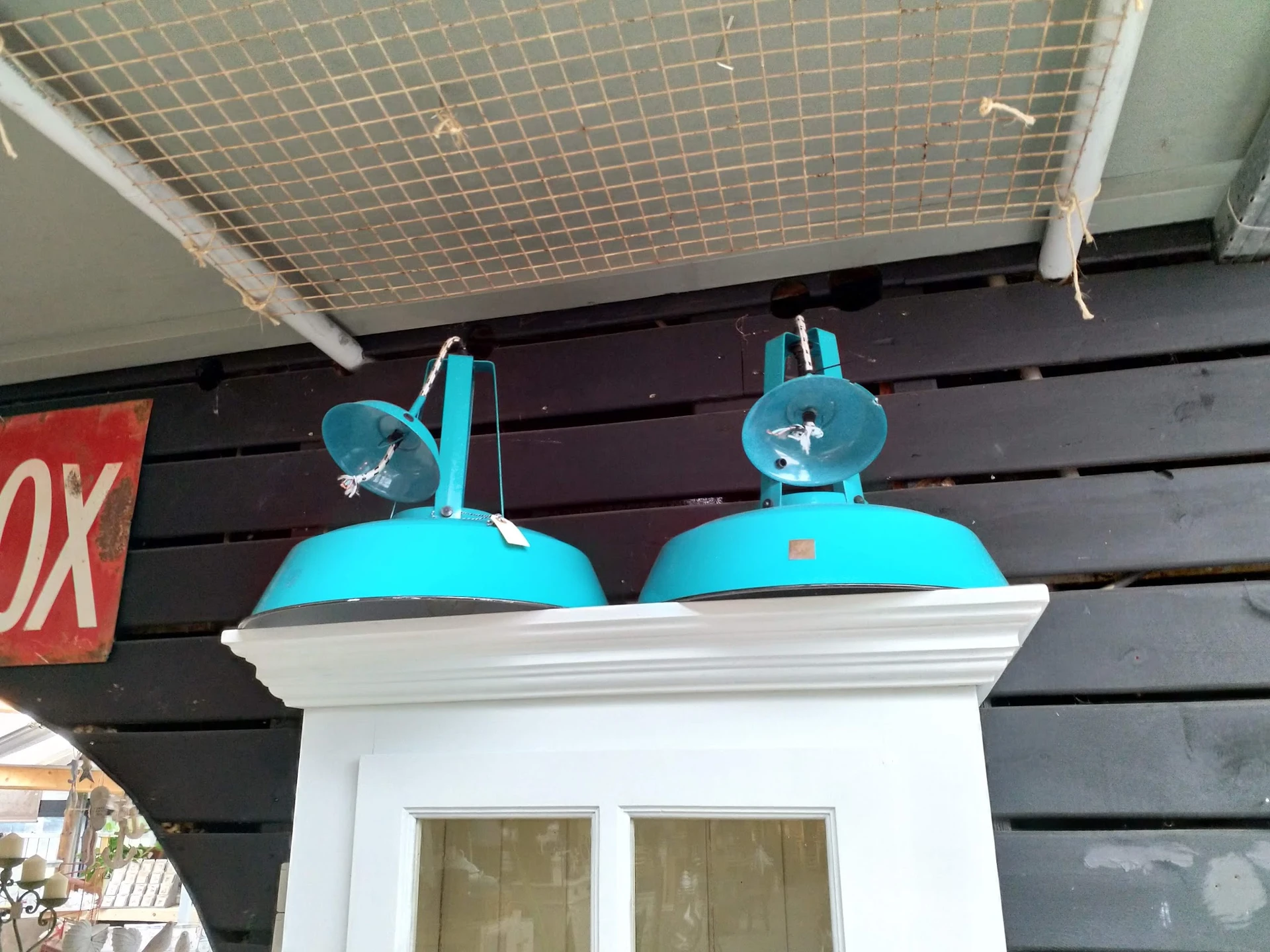 Twee turquoise industriële hanglampen op een witte plank tegen zwarte houten achtergrond
