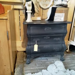 Zwarte vintage ladenkast met gebogen front en decoratieve details, uitgestald in de winkel