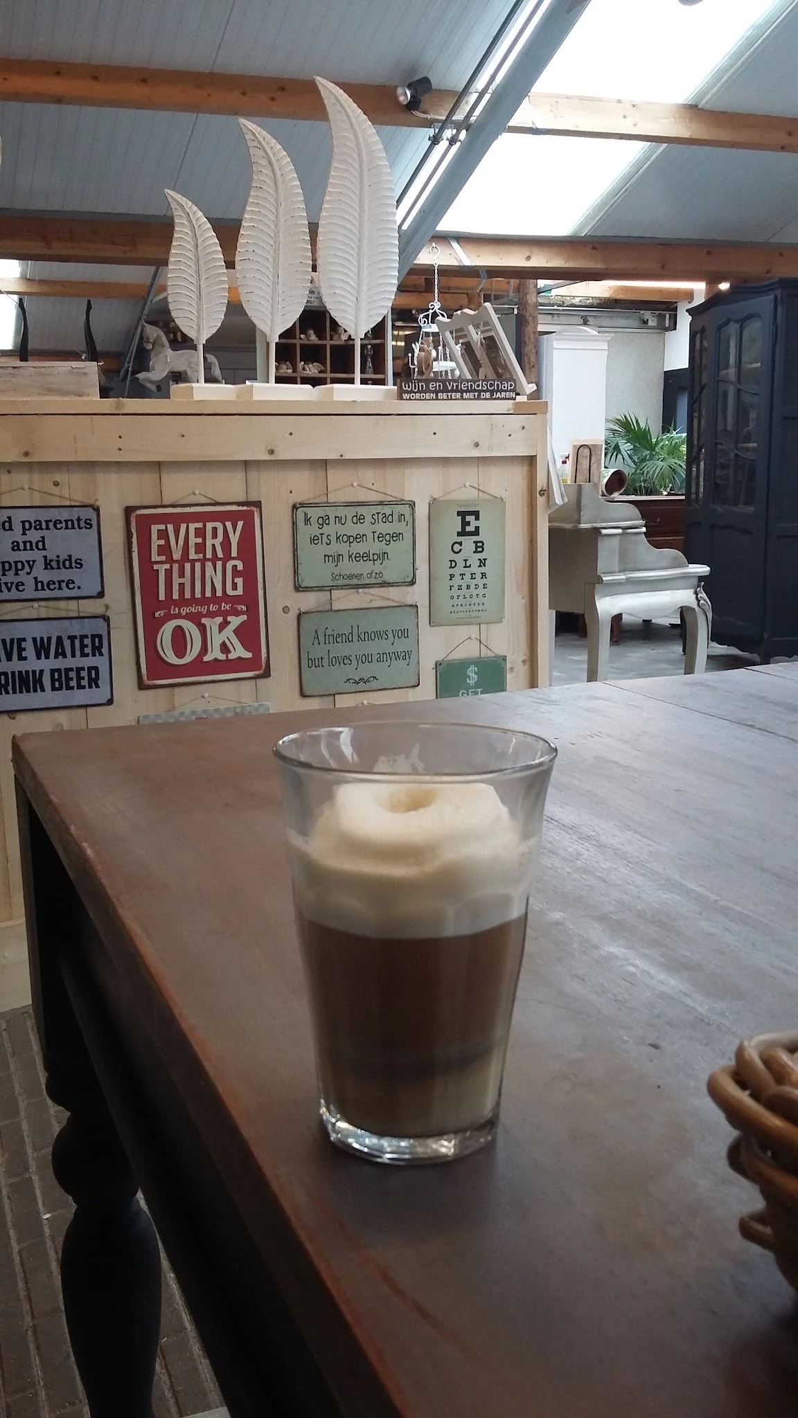 Glas met koffie en melkschuim op tafel in een koffiehoekinrichting