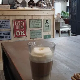 Glas met koffie en melkschuim op tafel in een koffiehoekinrichting
