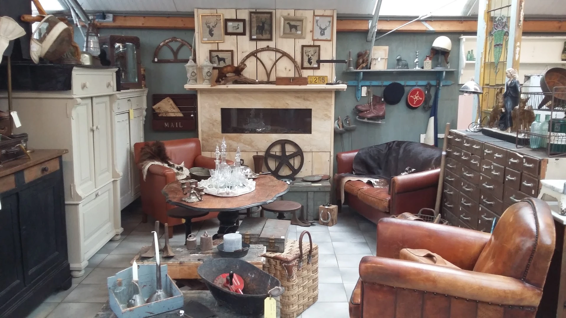 Ingerichte woonkamer met bruinleren fauteuils, haardmeubel met wanddecoratie en industriële accessoires