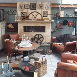 Ingerichte woonkamer met bruinleren fauteuils, haardmeubel met wanddecoratie en industriële accessoires