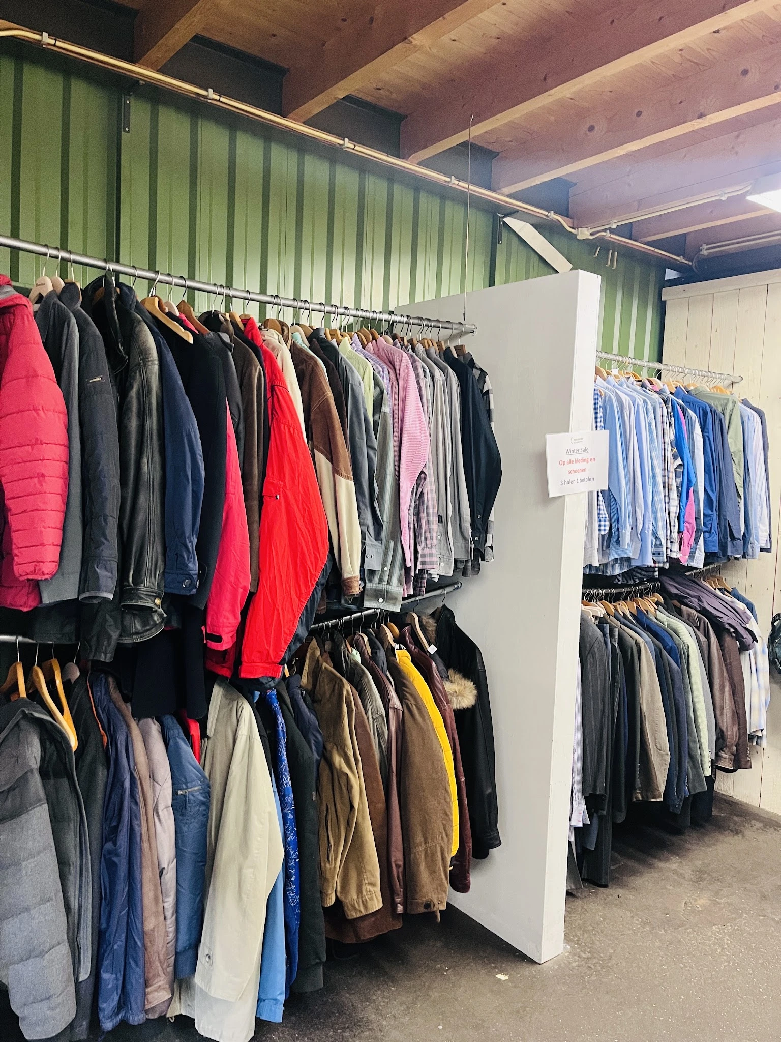 Rekken met tweedehands kleding in verschillende kleuren en stijlen
