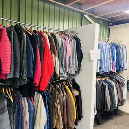Rekken met tweedehands kleding in verschillende kleuren en stijlen