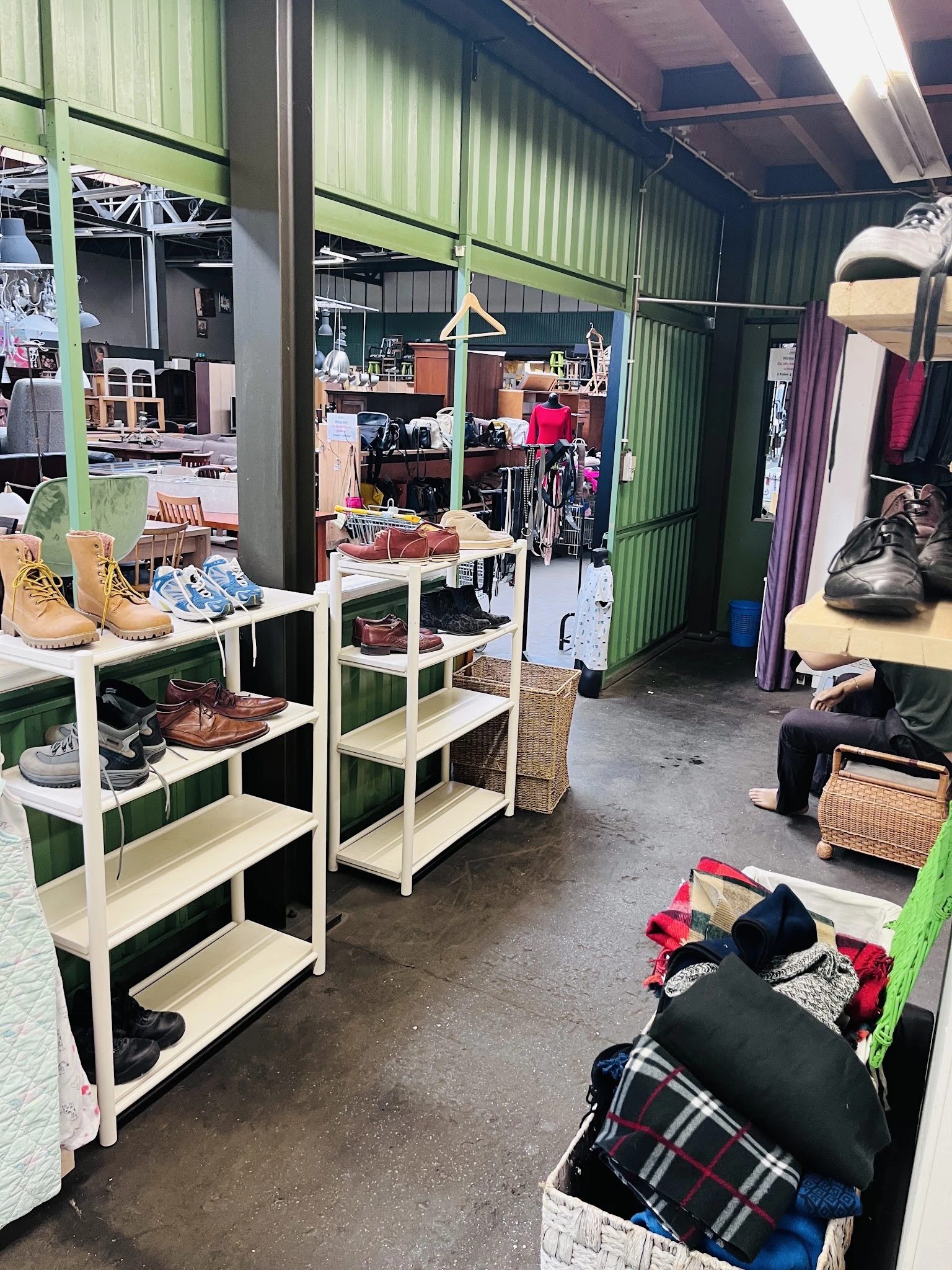 Winkelvloer met stellingen vol schoenen, kleding en huishoudartikelen in een kringloopwinkel