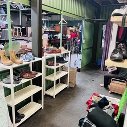 Winkelvloer met stellingen vol schoenen, kleding en huishoudartikelen in een kringloopwinkel