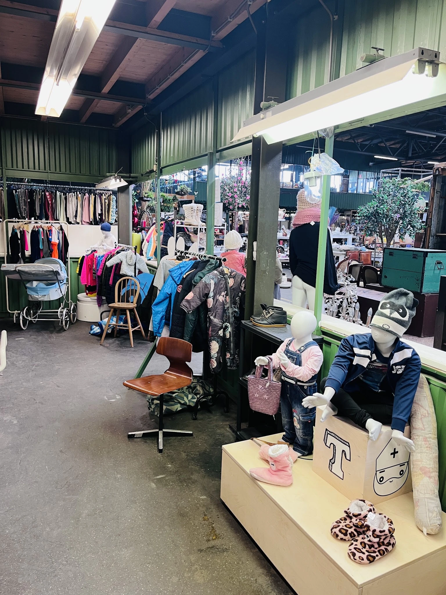 Winkelinterieur met kledingrekken, spiegels en diverse tweedehands kleding op hangers en in dozen