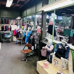 Winkelinterieur met kledingrekken, spiegels en diverse tweedehands kleding op hangers en in dozen
