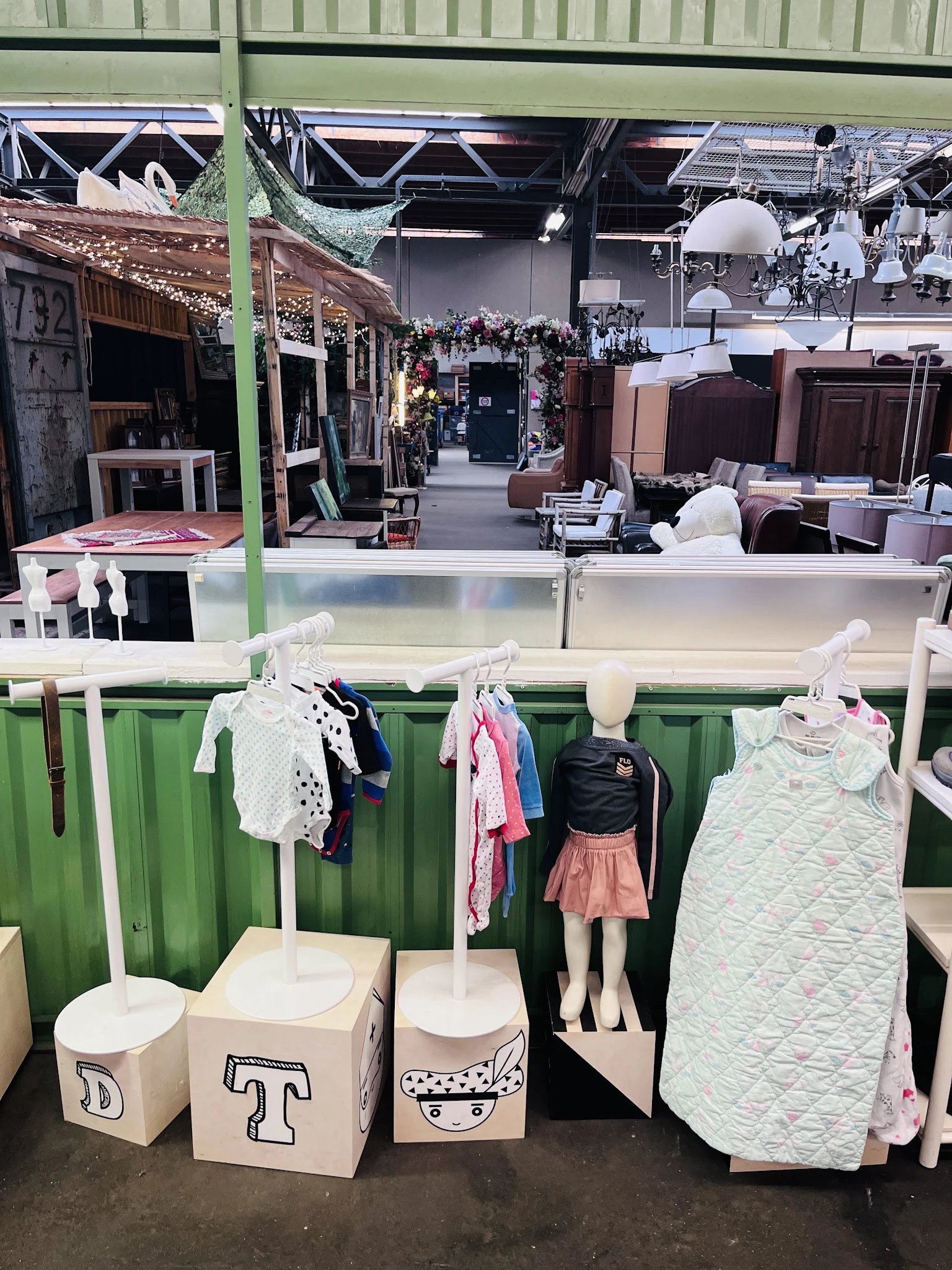 Kinderkledingafdeling met uitgestalde babykleding en kinderoutfits op hangers en paspop