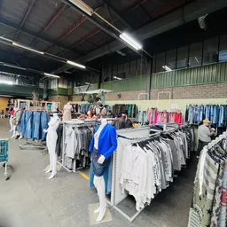 Winkelvloer met rekken vol tweedehands kleding, modepoppen en overzicht van de winkelafdeling