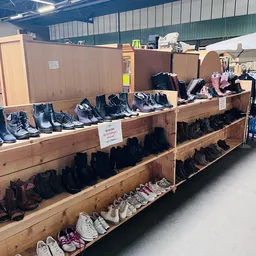 Houten stellingen met uitgestalde tweedehands schoenen en laarzen in verschillende kleuren en stijlen